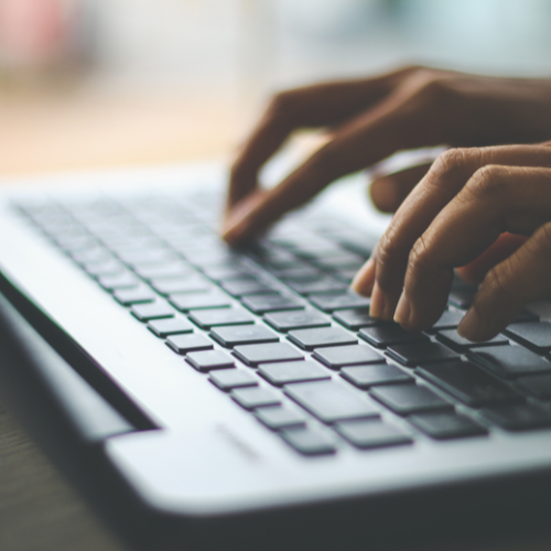 Hands typing on a laptop